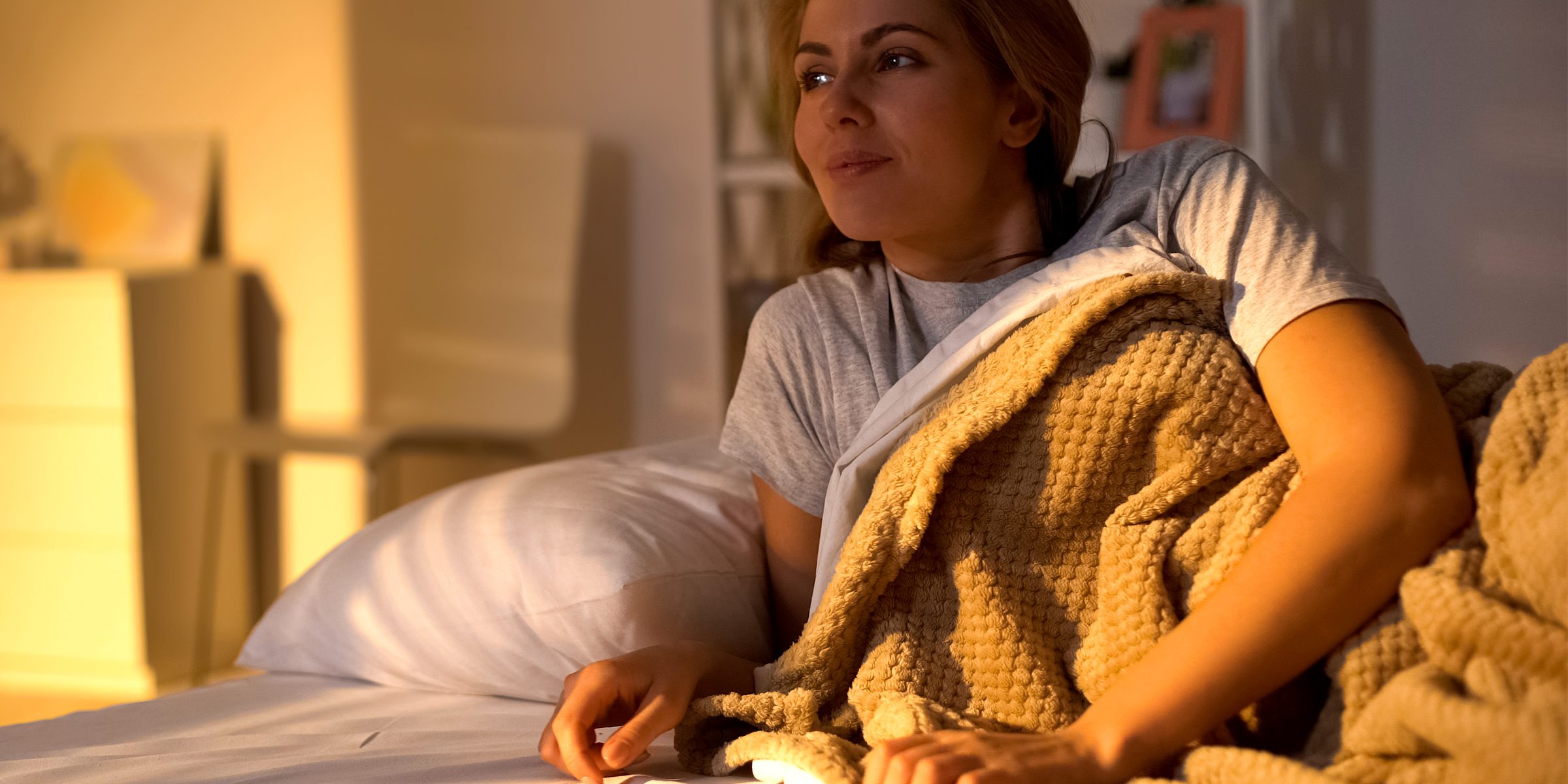 Attractive female waking up in bed in morning, greeting new day with smile